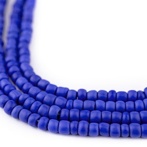 May include: Close-up of several strands of vibrant blue beads. The beads are small, cylindrical, and evenly spaced, creating a textured surface. The bright blue color contrasts against the white background, highlighting the beads' shape and color.