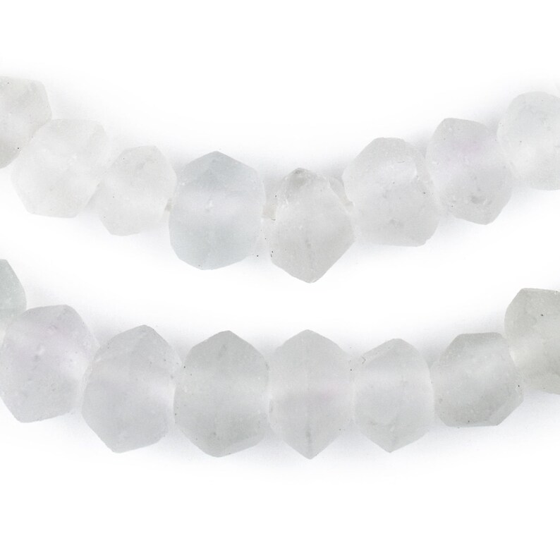 May include: A strand of opaque white glass beads with a faceted, hexagonal shape.