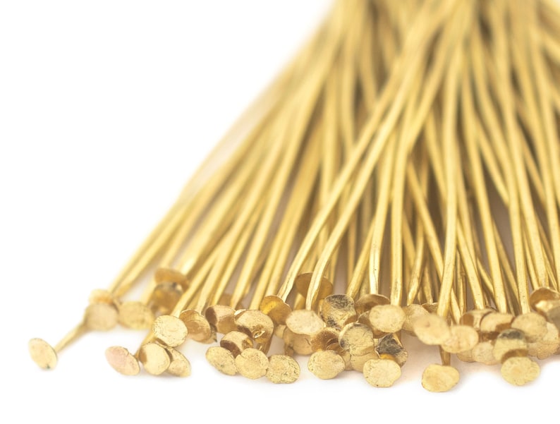 May include: A bunch of gold-coloured head pins with round heads. The pins are arranged in a fan shape.