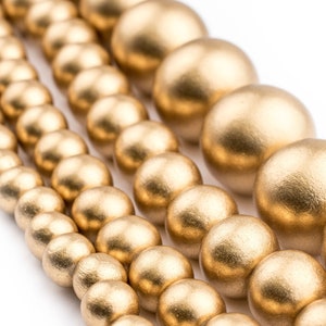 K&ouml;nnte beinhalten: Eine Reihe goldfarbener Holzperlen in verschiedenen Gr&ouml;&szlig;en. Die Perlen sind rund und haben eine glatte, matte Oberfl&auml;che.