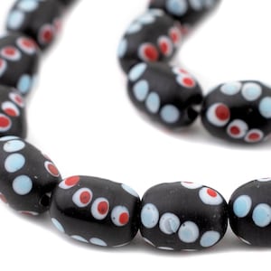 Puede incluir: Una hebra de cuentas de vidrio negro con lunares blancos y rojos.