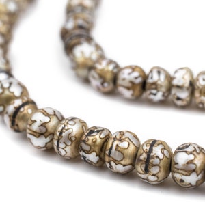 Könnte beinhalten: Nahaufnahme einer Halskette mit mehreren Perlen. Die Perlen sind eine Mischung aus Gold und Weiß mit einem einzigartigen Muster. Die Halskette befindet sich auf weißem Hintergrund. Die Perlen sind oval und aufgereiht.