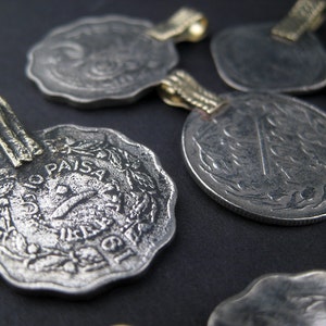 May include: A collection of six silver coins with gold loops, each featuring a different design and the inscription "10 Paisa".