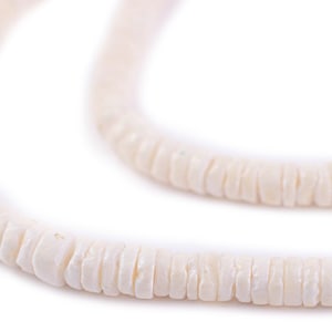 May include: A strand of white shell beads, strung together to form a necklace or bracelet. The beads are smooth and have a natural, organic look.