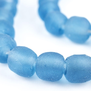 Puede incluir: Una hebra de cuentas de vidrio azul claro, cada cuenta tiene forma ovalada y un acabado mate.