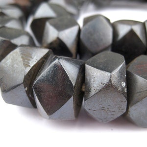 May include: A strand of black wooden beads, each bead is faceted and has a geometric shape.