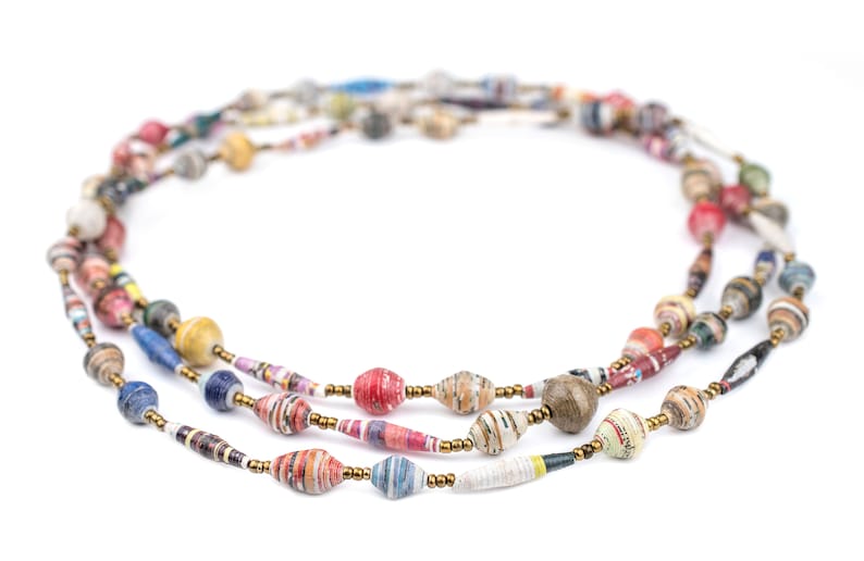 May include: A multi-strand necklace made of colorful paper beads. The beads are made of rolled up paper and are in various colors, including red, blue, green, yellow, and brown. The necklace is strung on a gold cord.