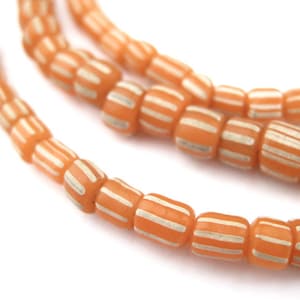 May include: A strand of orange glass beads with white stripes. The beads are cylindrical and have a matte finish.