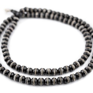 May include: A black beaded necklace with white accents. The beads are round and have a smooth finish.