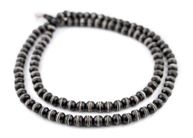 May include: A black beaded necklace with white accents. The beads are round and have a smooth finish.
