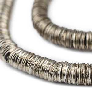 May include: A silver necklace made of many small, flat, round beads. The beads are stacked on top of each other to create a long, continuous chain.