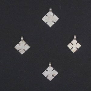 Pode incluir: Quatro pingentes de prata em forma de estrela de quatro pontas, cada um com um laço na parte superior para pendurar.
