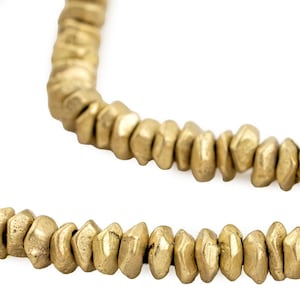 Puede incluir: Una hebra de cuentas de metal de color dorado. Las cuentas son facetadas y tienen una textura rugosa y martillada.