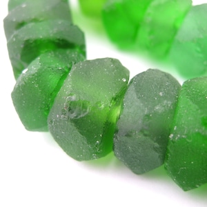 May include: A strand of green glass beads, each bead is faceted and has a slightly irregular shape.