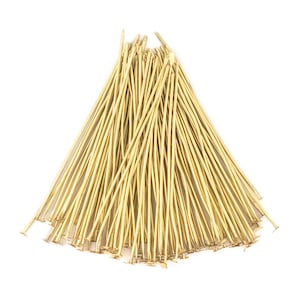 May include: A bunch of gold-coloured head pins with flat heads. The pins are arranged in a fan shape.