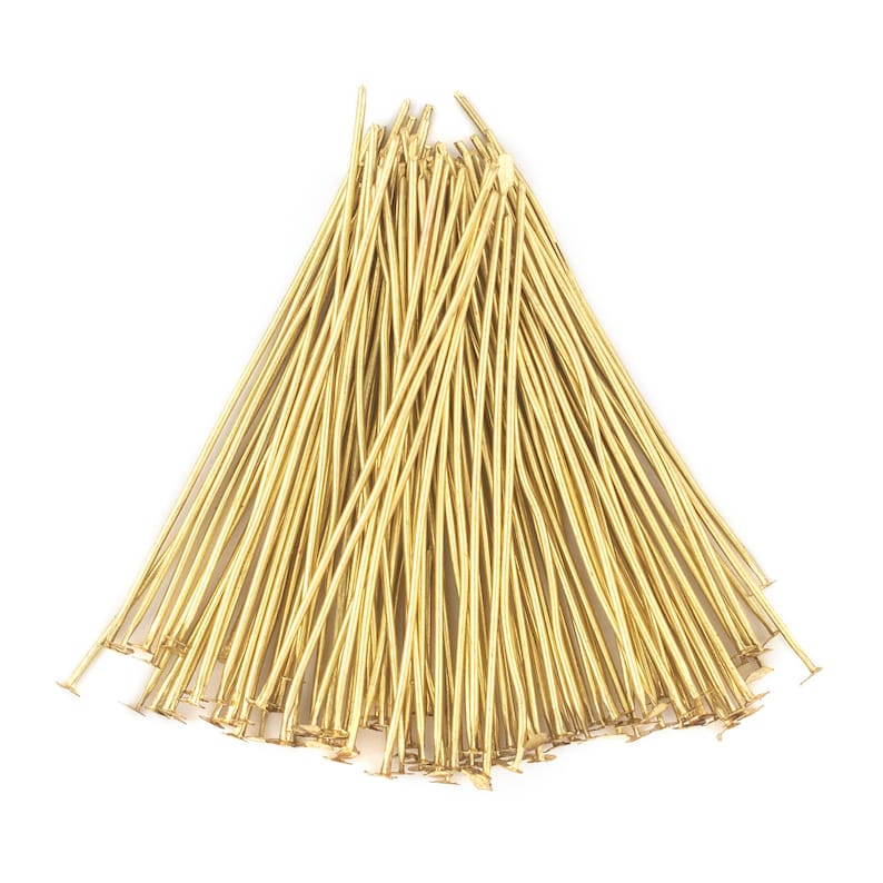 May include: A bunch of gold-coloured head pins with flat heads. The pins are arranged in a fan shape.