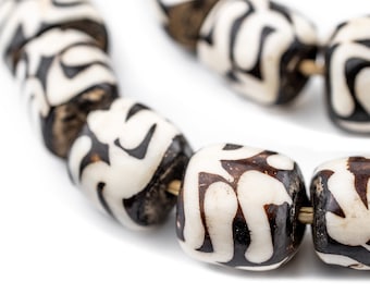 May include: A close-up of a necklace made of white and brown beads with a geometric pattern. The beads are strung on a gold cord.