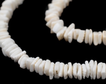 Op de afbeelding: Een witte schelpenketting gemaakt van platte, rechthoekige schelpen. De ketting is aan elkaar geregen met een dun, wit draad.