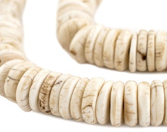 Op de afbeelding: Close-up van een crèmekleurige ketting gemaakt van ronde, platte kralen. De kralen hebben een natuurlijke uitstraling met subtiele bruine adering. De ketting is in een gebogen vorm geplaatst tegen een witte achtergrond.