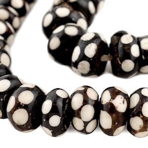 May include: A black and white beaded necklace with round beads featuring a polka dot pattern.