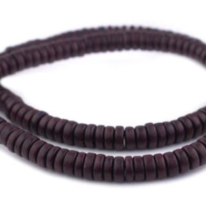 K&ouml;nnte beinhalten: Eine Schnur aus dunkelbraunen Holzperlen, jede Perle hat die Form eines flachen Rings.