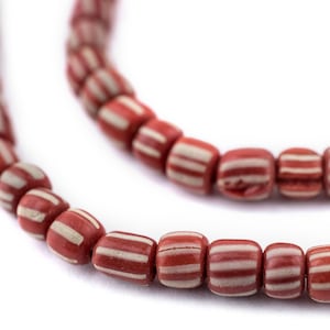 May include: A strand of red and white striped beads. The beads are made of clay and have a matte finish.