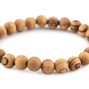 May include: A beaded bracelet made of light brown wooden beads. The beads are round and have a natural wood grain pattern. The bracelet is strung on an elastic band and is displayed on a white background.