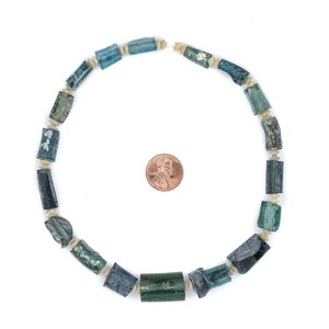 May include: A necklace made of green and white cylindrical beads. The beads are arranged in a circle and are about the size of a US penny.