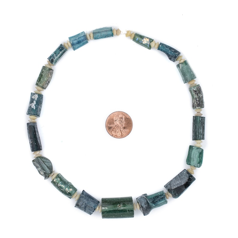 May include: A necklace made of green and white cylindrical beads. The beads are arranged in a circle and are about the size of a US penny.