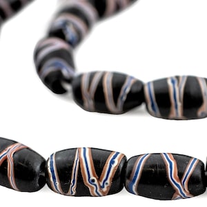 May include: A strand of black glass beads with white, blue and pink stripes. The beads are oval shaped and have a glossy finish.