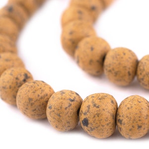 May include: A string of brown speckled beads, possibly made of wood or stone. The beads are round and have a natural, rustic look.