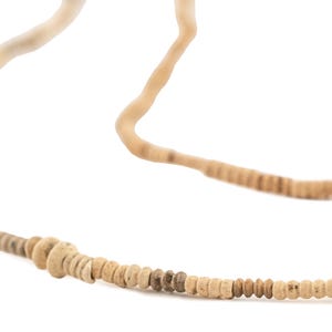 May include: A necklace with small, round, light brown beads. The beads vary in colour, with some darker than others. The necklace has a natural, earthy aesthetic, with a simple design.