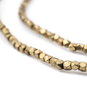 May include: A strand of gold-toned metal beads, each bead is faceted and has a hexagonal shape.
