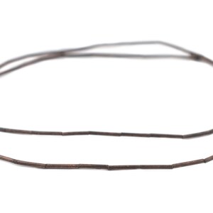 Pu&ograve; includere: Una collana di perline di metallo marrone, ogni perlina &egrave; un piccolo cilindro. Le perline sono infilate per formare una collana.