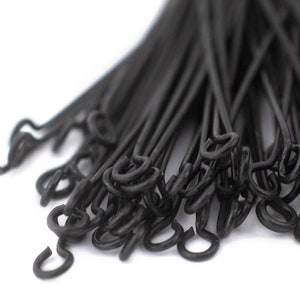May include: A close-up of a bundle of black cable ties with a hook on one end. The ties are twisted together and the hooks are visible.