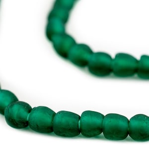 May include: A strand of dark green glass beads. The beads are oval shaped and have a frosted finish.