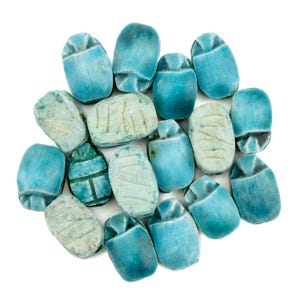 Può includere: Una collezione di figurine di scarabei turchesi, ognuna con incisioni dettagliate. Gli scarabei variano in tonalità, dal turchese chiaro allo scuro, alcuni mostrano segni di età. La disposizione è sparsa su uno sfondo bianco, evidenziando i disegni intricati.