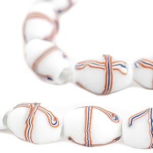 Puede incluir: Cuentas ovaladas blancas con un diseño en forma de cruz en rojo y azul. Las cuentas están ensartadas, creando un collar o pulsera. El diseño es simétrico y las cuentas tienen un acabado liso y brillante.