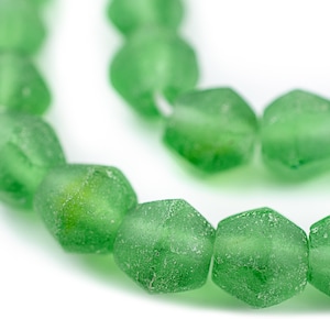 Könnte beinhalten: Eine Strähne grüner Glasperlen mit einer facettierten, unregelmäßigen Form. Die Perlen haben eine gefrostete, strukturierte Oberfläche.