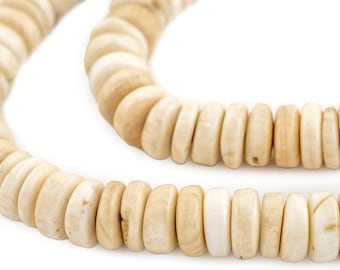 Op de afbeelding: Close-up van een ketting gemaakt van ronde, gebroken witte kralen. De kralen hebben een natuurlijke, organische uitstraling met kleurvariaties, variërend van licht crèmekleurig tot een iets donkerdere bruintint. De ketting wordt getoond tegen een witte achtergrond.