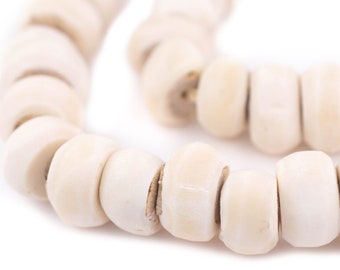 May include: A close-up of a white beaded necklace made of smooth, round beads. The beads are strung together on a thin cord and are arranged in a loose, flowing pattern.