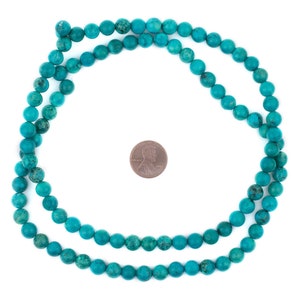 May include: A strand of turquoise beads, approximately 16 inches long, with a penny for scale.