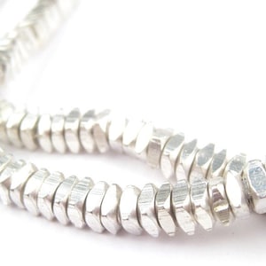 May include: A strand of silver beads, each bead is faceted and has a hexagonal shape.