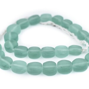 May include: A strand of light blue glass beads, each bead is oval shaped and frosted.