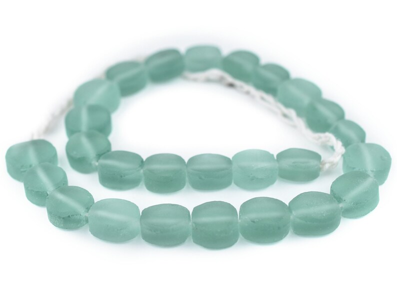 May include: A strand of light blue glass beads, each bead is oval shaped and frosted.