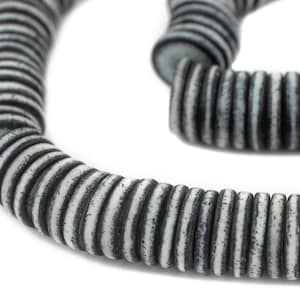 May include: A close-up of a black and white striped ceramic bead necklace. The beads are round and have a textured surface.