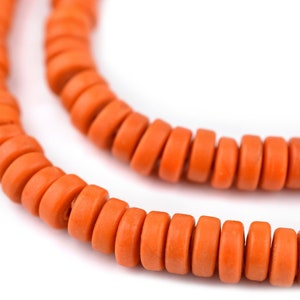 May include: A strand of orange wooden beads, strung together to form a necklace or bracelet. The beads are round and have a slightly textured surface.