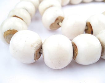 May include: A strand of white ceramic beads with brown accents. The beads are round and smooth, and they are strung together on a white cord.