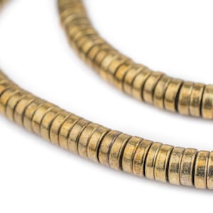 以下が含まれることがあります： 小さな丸いビーズでできたゴールドトーンのネックレス。ビーズは連続して重なり合ったパターンで配置されており、質感のある外観になっています。