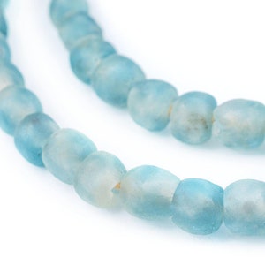 Può includere: Una collana di perline di vetro blu chiaro. Le perline sono opache e hanno una finitura leggermente opaca.